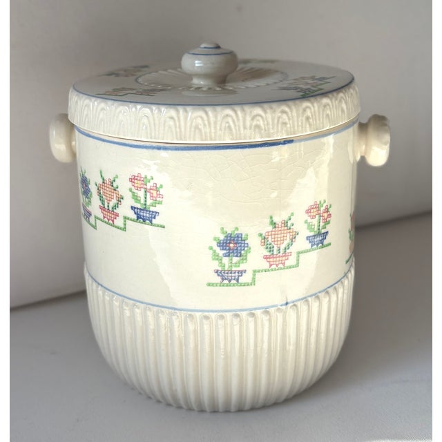This charming ceramic biscuit jar features dimensional ribbing around its lower half , blue pin stripping, round ceramic...