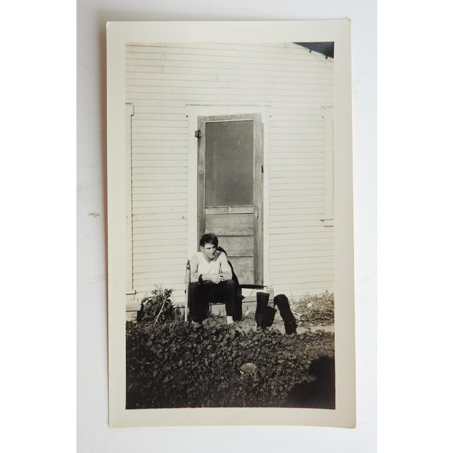 Early 20th century snapshot photograph of lonely man smoking a cigarette sitting on door step. Unframed.