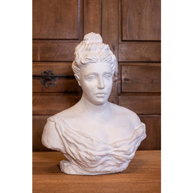 An Italian bust of a woman wearing a sleeveless and creased dress attached with a fibula. This elegant 20th-century...