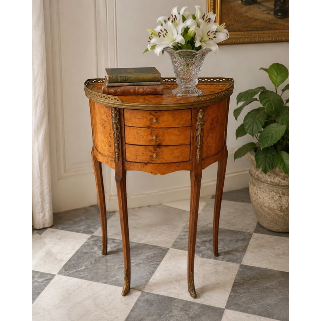 Charming vintage French-style demilune side table featuring richly figured burl wood veneers and elegant brass detailing....