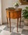 Charming vintage French-style demilune side table featuring richly figured burl wood veneers and elegant brass detailing....