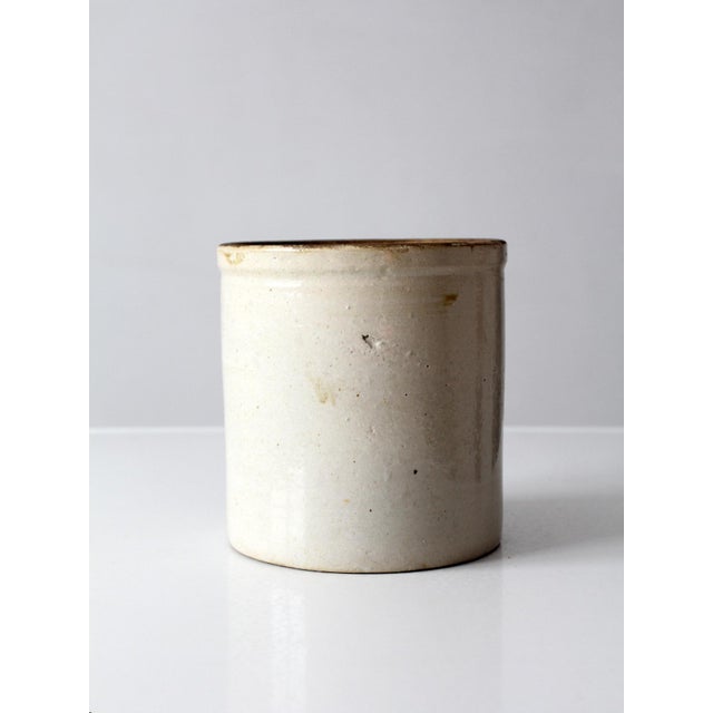 Charming antique stoneware crock featuring a creamy white exterior and richly contrasting deep brown glazed interior....