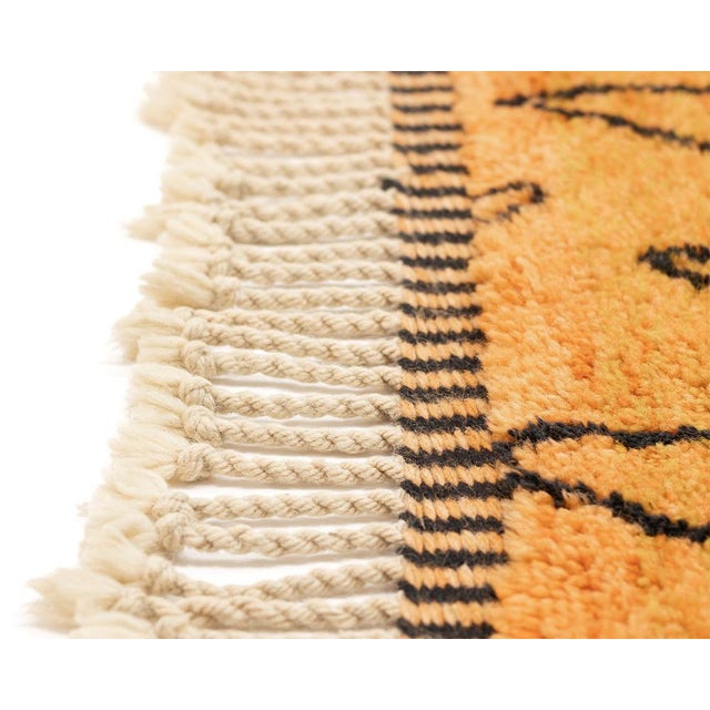 A forest at dusk, rendered in black lines against a saffron sky. This hand-knotted wool rug depicts a striking silhouette...