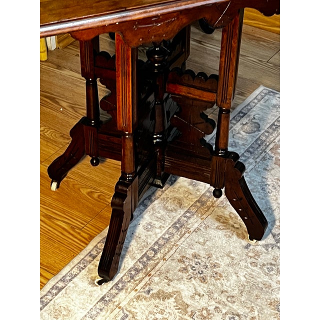 Eastlake center parlor table in excellent condition. Walnut with carved detailing & white ceramic caster also in excellent...