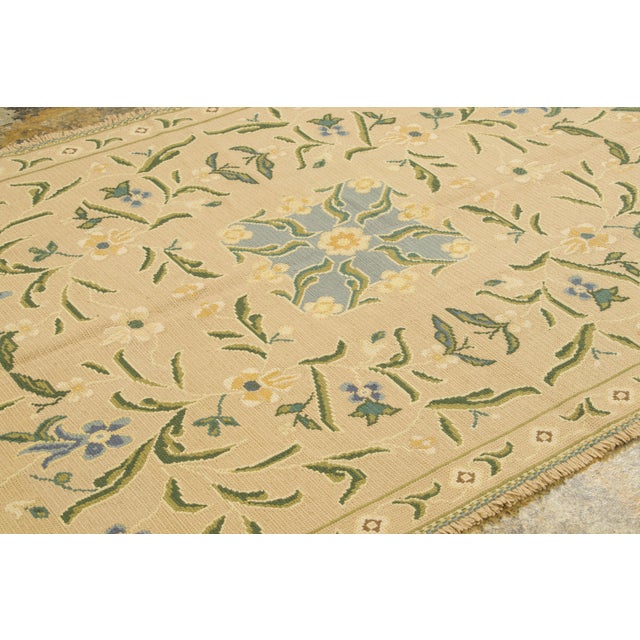 Handmade in wool, this 5x9 vintage Portuguese Arraiolos needlepoint rug originating circa 1950-1959 is a charming addition...