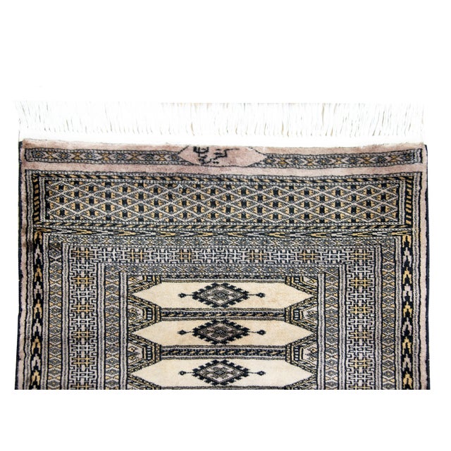 A vintage late 20th century Pakistani Bokhara rug with six large long central medallions surrounded by multiple thin and...