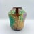 A richly glazed art pottery vase featuring dimensional wisteria blossoms and trailing leaves modeled in relief across the...
