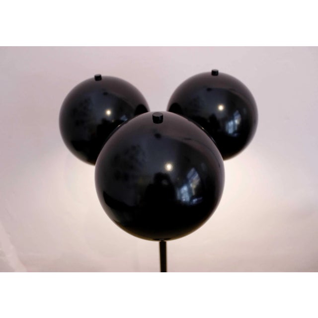 This Totemball floor lamp, with three lacquered steel balls in black, diffuses an indirect light, and has a cord of red...