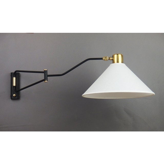 Small wall lamp in brass and black lacquered metal consisting of two articulated arms and a ball joint mounted on the...