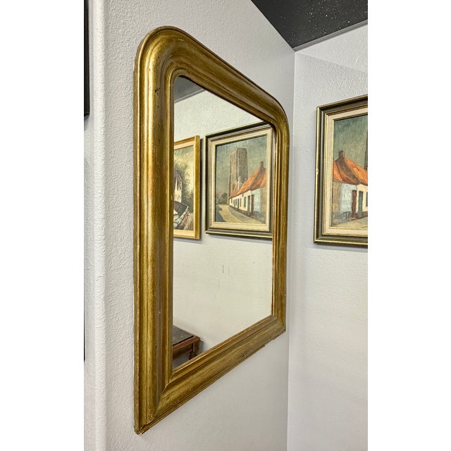 This antique French Louis Philippe mirror features gilded wood with the characteristic arch and original mirror and wood...