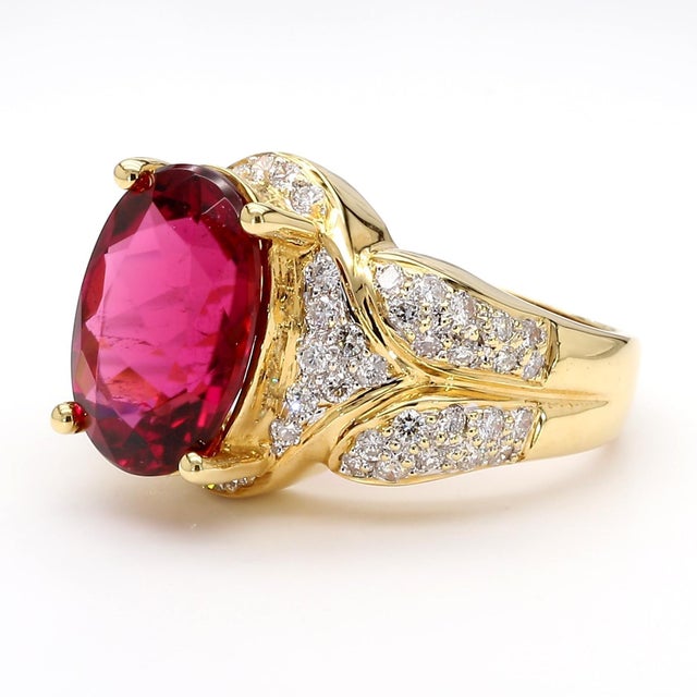 Vintage 10.5-carat oval-cut rubellite tourmaline takes center stage in this 18K yellow gold cocktail ring, complemented by...