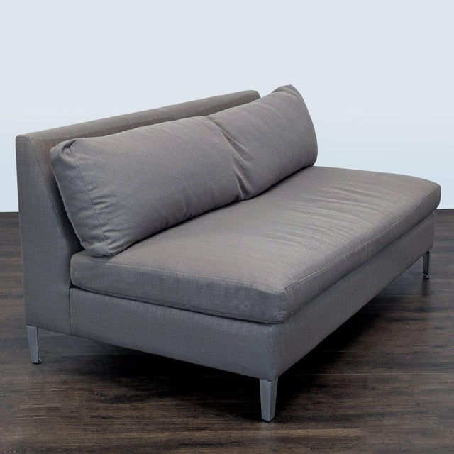 This CB2 loveseat features a sleek and modern design with a gray fabric finish and sturdy metal legs. Its wide cushioned...