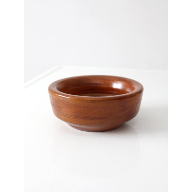 A beautifully understated vintage turned wood bowl, distinguished by its substantial rounded rim and richly varied natural...