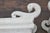 A pair of Rococo style Continental 1920s white painted ottomans with S-Scroll legs. Elevate your home with this stunning...