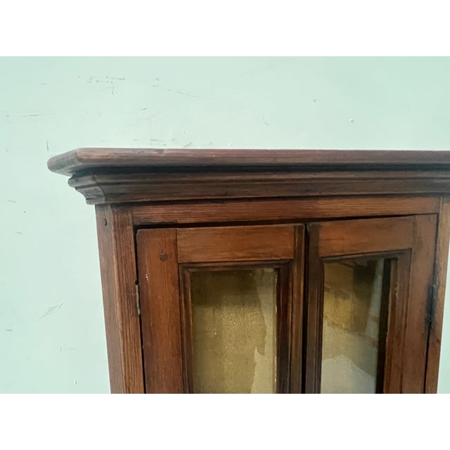 Small wall-mounted display cabinet with two natural wood doors Two glass doors on the front Good condition Dimensions: H...