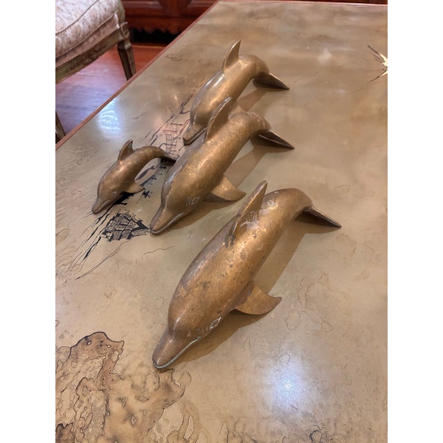 A set of four brass dolphins in brass, Nice, natural brass patina, which can be polished. Three larger dolphins and one...