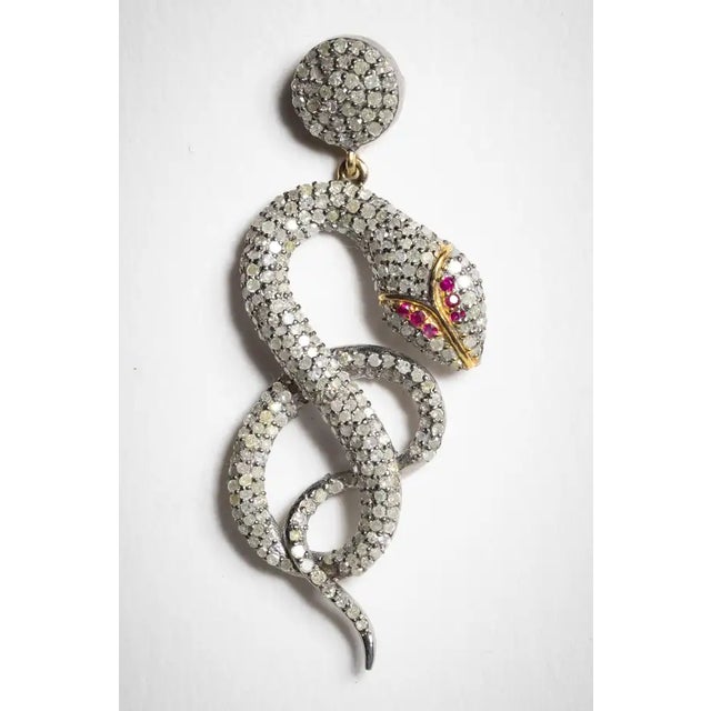 An incredible pair of coiled snake diamond earrings with ruby eyes. The diamonds are round, brilliant cut diamonds in a...