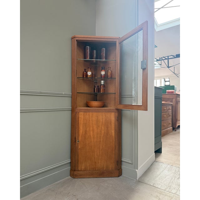 This vintage oak corner cabinet with glass doors is a beautiful example of french furniture from the interwar period:...
