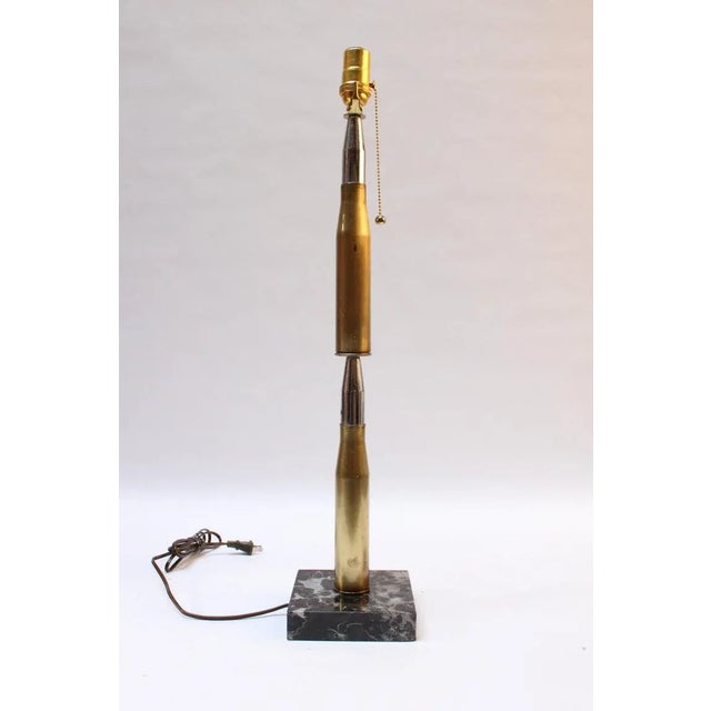Trench Art lamp fashioned from two stacked brass and chrome high caliber artillery shells mounted to a black marble base...