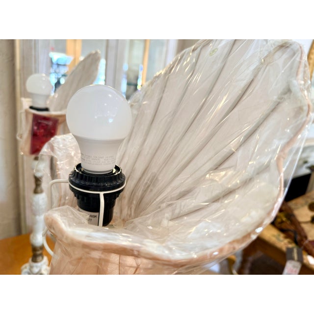 A striking pair of new porcelain table lamps featuring sculptural white glazed bases with ornate scrolling detail, turned...