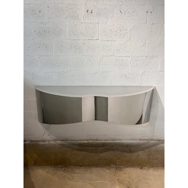 Custom polished steel floating wall console or shelf with frosted lucite top circa 1970s. A welded steel bracket on the...