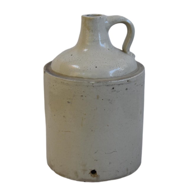 Beautifully balanced antique stoneware jug with a primitive design, featuring a rich, cream-colored cylindrical body....