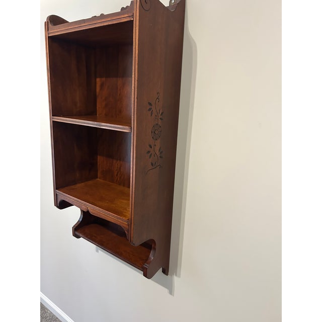 A charming Victorian-period walnut wall shelf, circa 1880s, featuring three graduated shelves, a scalloped crest rail with...