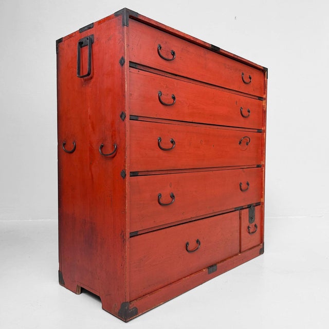 A Japanese chest of drawers in warm orange-red, with a timeworn finish and dark metal fittings. Weight: approx. 38kg...