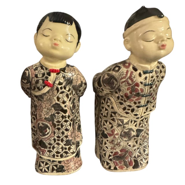 These decorative figurines represent Chinese children in traditional clothing, featuring intricate floral and geometric...