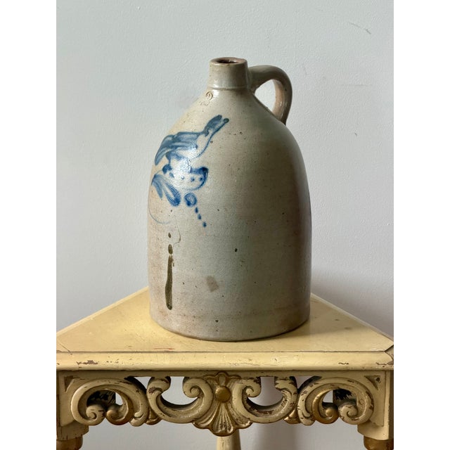 Large 19th century stoneware jug with a single handle, narrow mouth, cobalt blue bird/floral decoration, and an impressed...