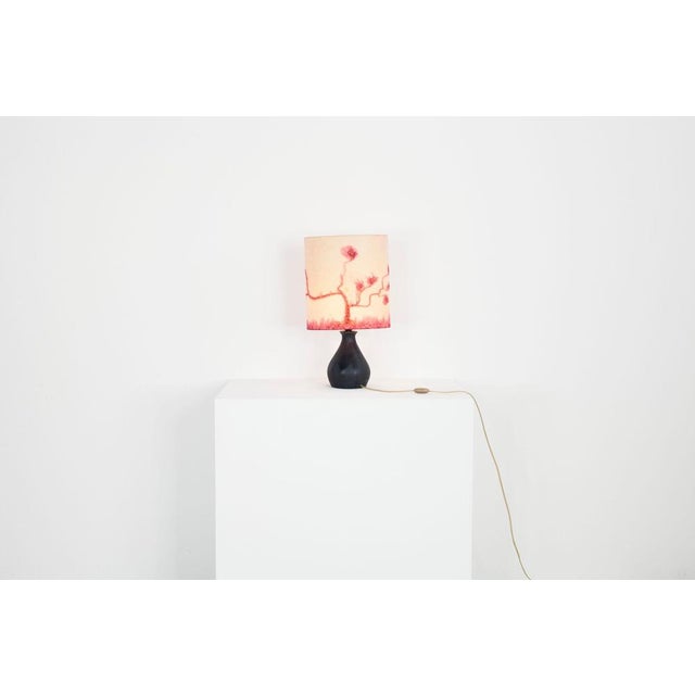 70s table lamp with black ceramic base and a silk covered lampshade with batik pattern. European Plug (up to 250V).The...