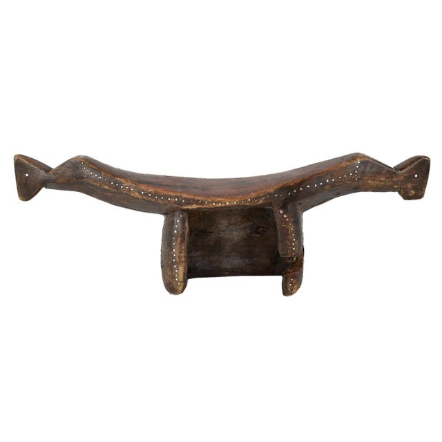 The Dinka headrest under consideration exhibits a stylized zoomorphic shape, with a uniquely formed hollow back and ends...