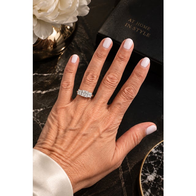 A clean and timeless three-stone diamond ring with a modern edge. This piece features three well-matched princess-cut...