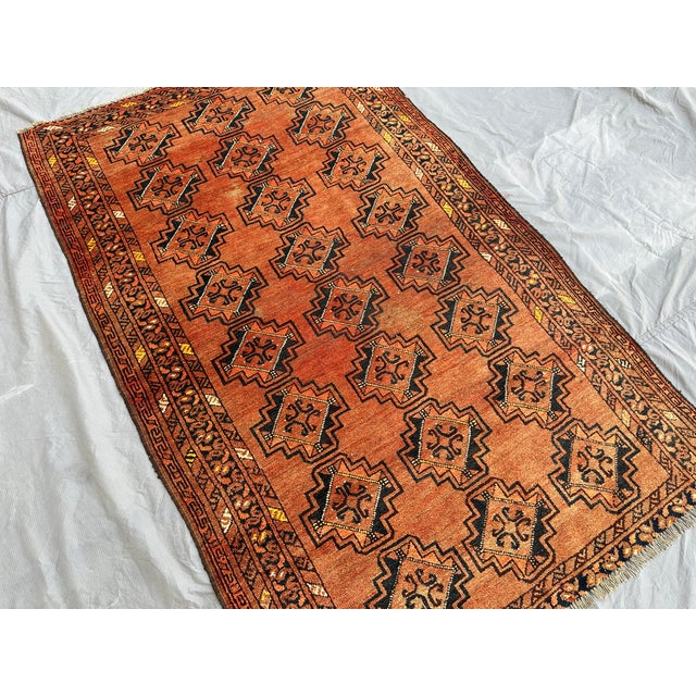 This hand-knotted Baluch rug features an allover lattice of stepped diamond medallions, each filled with a small scrolling...