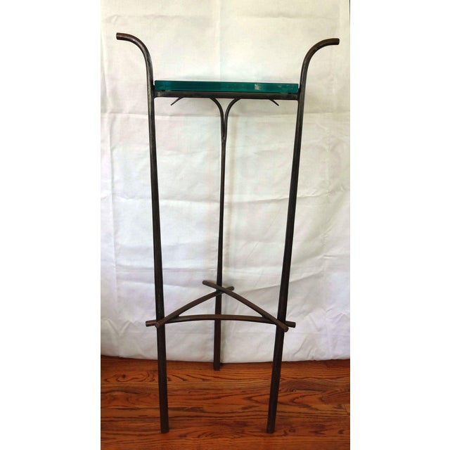 A unique hand forged iron pedestal with a 3/4 inch glass top. The stand is a gunmetal gray with a waxed patina that has a...