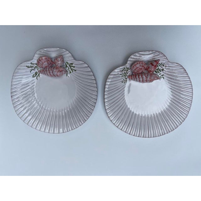 A matching pair of shell shaped majolica pottery plates featuring applied trompe l'oeil shells.