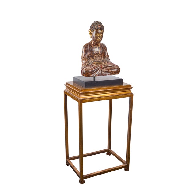A striking, hand-carved, painted and parcel gilt, seated Buddha mounted on a laminated wooden base, with gilt-wood...