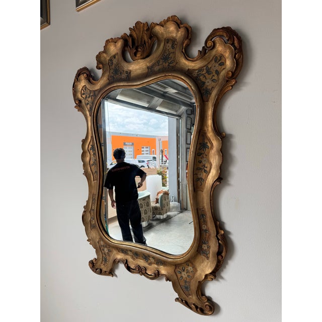 Elegant and highly decorative 1960’s Italian Hollywood Regency wall mirror, featuring an elaborately carved wood frame...