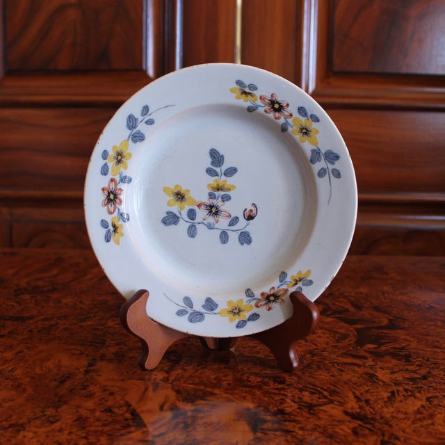 A floral decorated English Delftware plate painted in a distinctive palette of chrome yellow with touches of red oxide and...