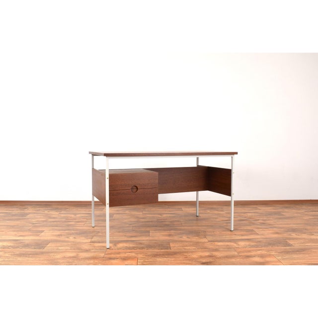 This desk was manufactured in Denmark in the 70s. Wooden elements are made of teak wood and frame is made of beige-gray...