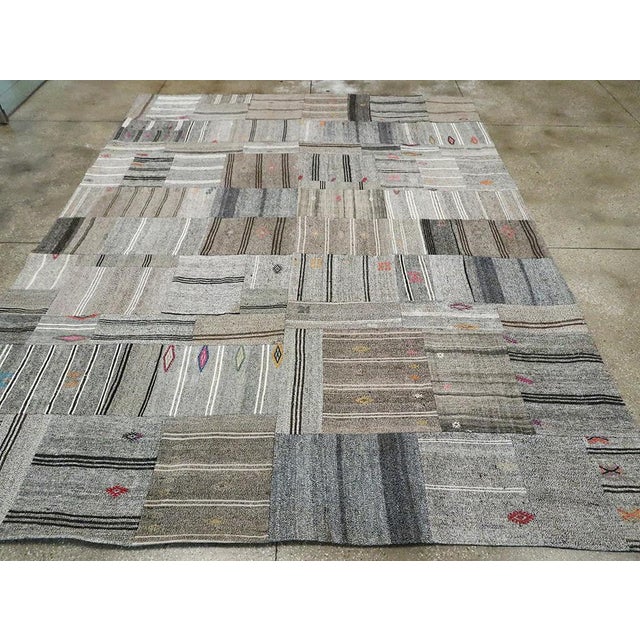 This Mid-20th century Turkish Flatweave Kilim rug, presents a captivating patchwork design composed of handwoven Kilim...