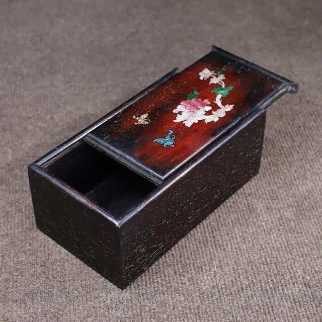A beautifully crafted Chinese rectangular box, likely made of Huali (rosewood). The box features a sliding lid that opens...