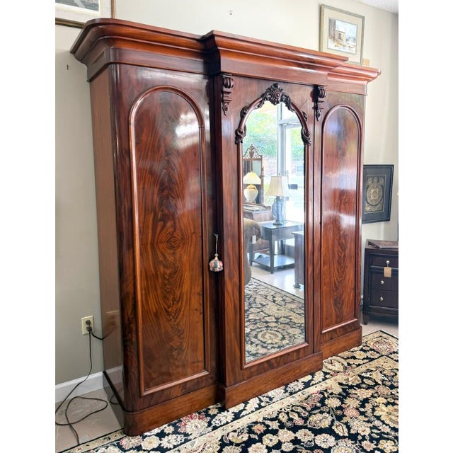This impressive 19th Century Triple Wardrobe showcases richly figured flamed mahogany, arched panel doors, carved...