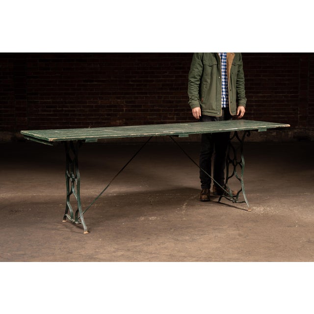 Long, narrow trestle table constructed from solid oak planks set atop a pair of cast iron folding-style bases with...