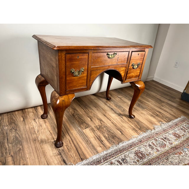 This antique George III Queen Anne mahogany lowboy dates to the late 18th century and is a classic example of English...