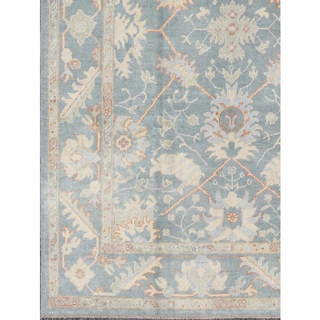 Turkish Oushak rug with floral design in light steel blue and coral accent This piece is made with a combination of old...