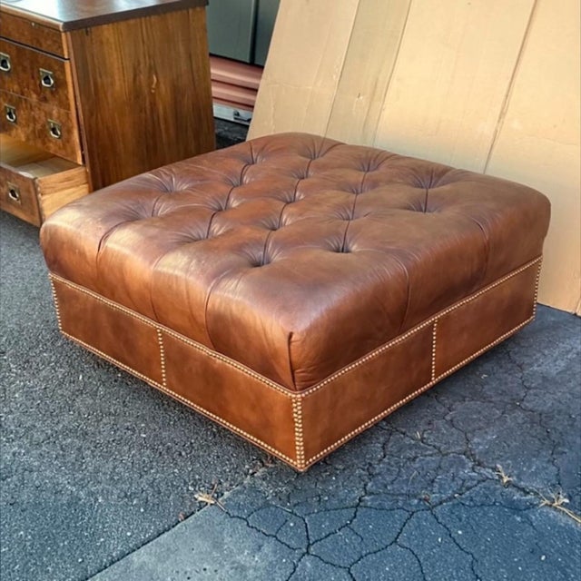 This is a late 1990s Hancock and Moore tufted leather Chesterfield style square ottoman. It is a nice patinated whiskey...