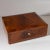Small rectangular casket with slightly beveled lid and filling-shaped veneer pattern made of walnut. The casket stands on...