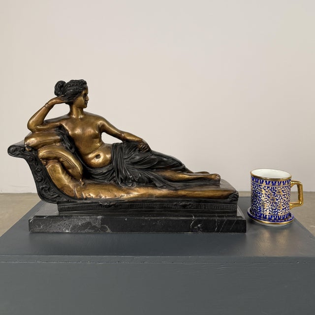 Elegant bronze sculpture depicting a reclining female figure on an ornate chaise lounge, in a style inspired by 19th-...