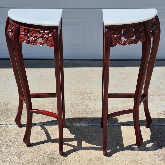 This is a beautifully carved pair of red mahogany corner tables or pedestals with white stone tops. Unmarked but likely...